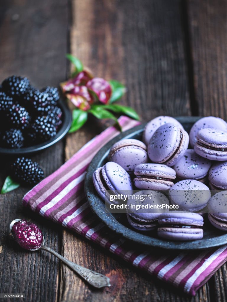 Blackberry macarons on a rustic wooden table.