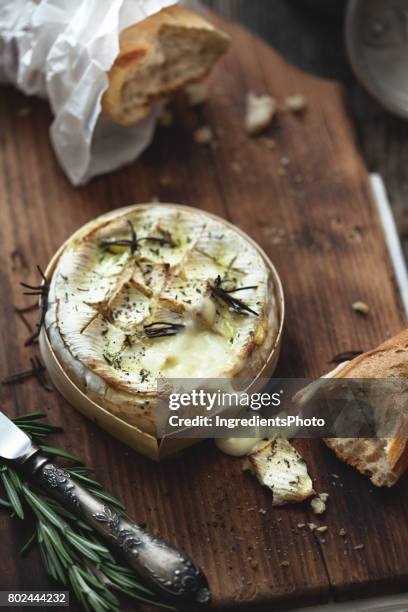 gebackener camembert im ofen mit kräutern auf einem holztisch. - camembert stock-fotos und bilder