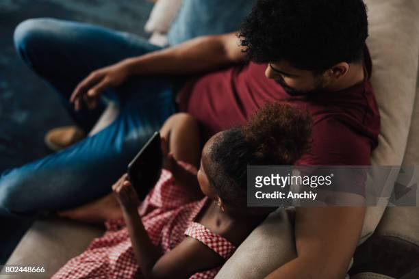 Father hugs his daughter while she's holding digital tablet