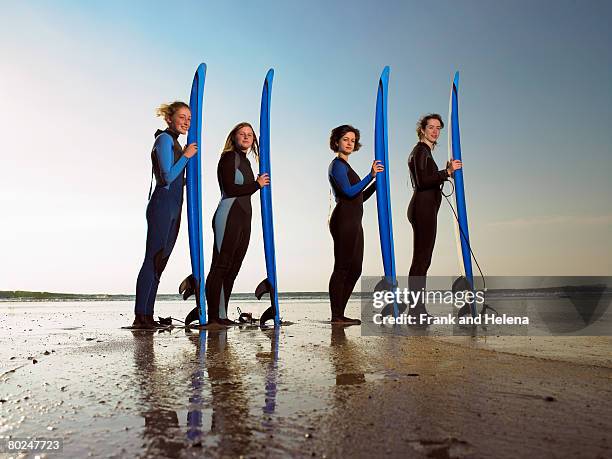 four female surfers standing on a beach. - croyde beach stock pictures, royalty-free photos & images