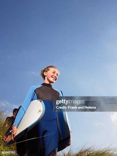 female surfer walking through grass. - croyde beach stock pictures, royalty-free photos & images