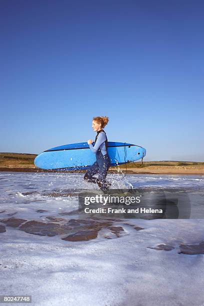 female surfer running into the water. - croyde beach stock pictures, royalty-free photos & images
