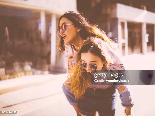 young women giving a piggyback ride in old city streets - giving a girl head stock pictures, royalty-free photos & images