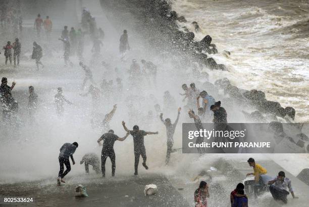 People gather by the Marine Drive seafront to be hit by breaking waves at high tide in Mumbai on June 28, 2017.