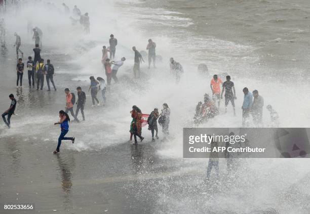 People gather by the Marine Drive seafront to be hit by breaking waves at high tide in Mumbai on June 28, 2017. / AFP PHOTO / PUNIT PARANJPE