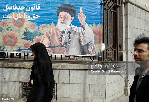 Man and woman walk past a banner of supreme leader Ayatollah Sayed Ali Khamenei as Iranians vote in elections for the 8th "majlis" or parliament...