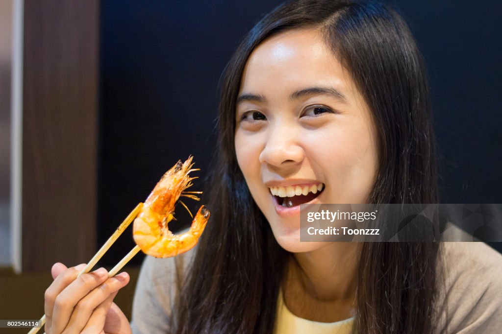 Asian woman eating with chopsticks