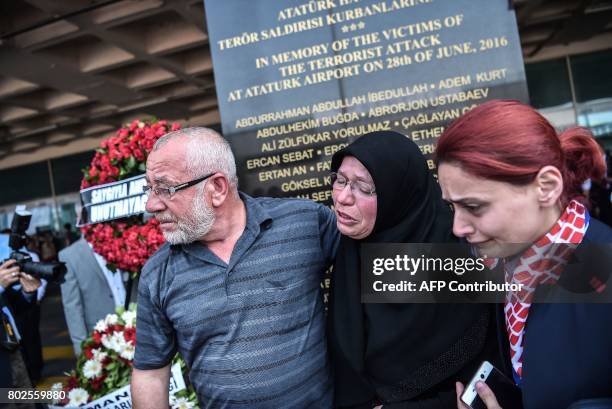 Woman is helped as she reacts during a memorial ceremony on June 28, 2017 at Ataturk International airport in Istanbul, one year since the triple...