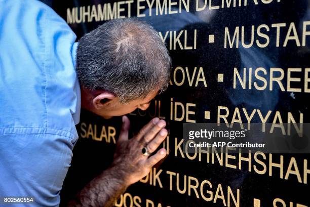 Grieving man touches a commemorative plaque during a memorial ceremony on June 28, 2017 at Ataturk International airport in Istanbul, one year since...