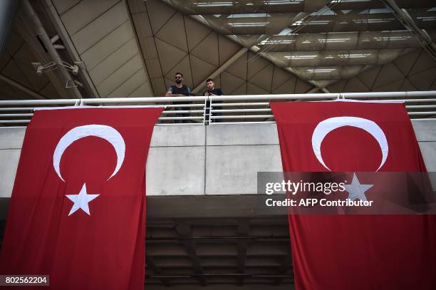 Turkish police officers stand guard by Turkey's national flags within a memorial ceremony on June 28, 2017 at Ataturk International airport in...