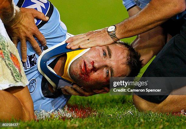 Ben Ross of the Sharks is placed in a neck brace by medical staff after being knocked out in a tackle during the round one NRL match between the...