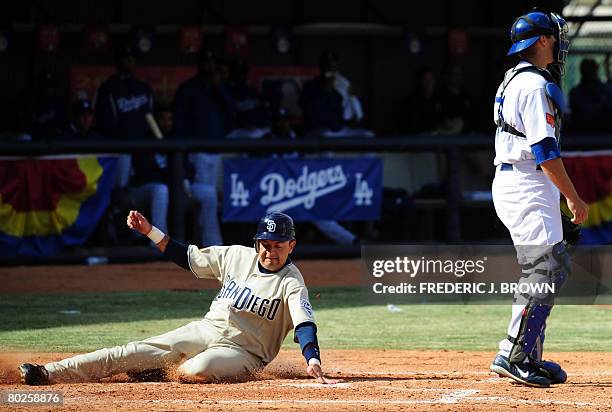 Oscar Robles of the San Diego Padres scores from third as Los Angeles Dodgers catcher Lucas May looks on during the first Major League Baseball game...