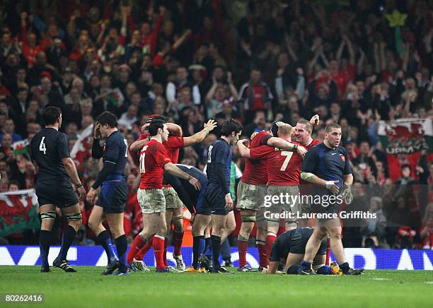 Wales players celebrtate their Grand Slam as dejected French players look on during the RBS Six Nations Championship match between Wales and France...