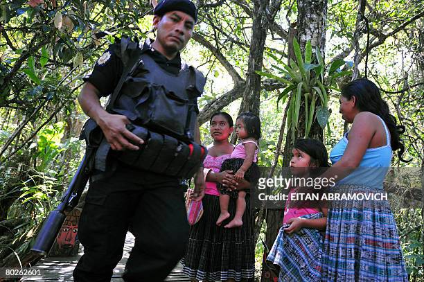 Guatemalan policeman walks past some members of the Mayan community of Lagunilla El Salvador in Rio Dulce, some 250 km northeast of Guatemala City on...