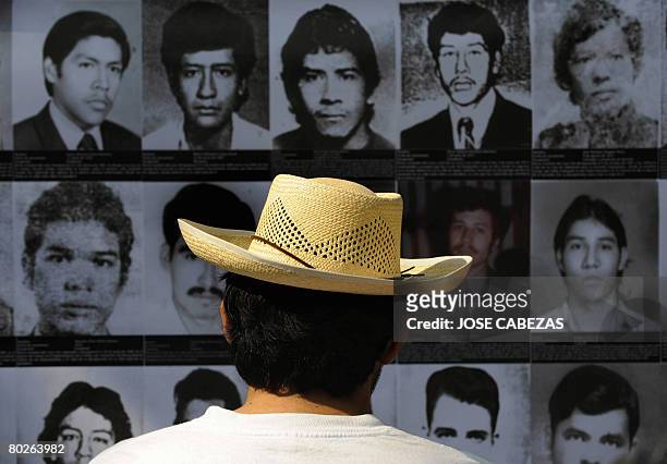 Salvadorean Carlos Tejada looks at portraits of people who dissappeared for political reasons during the civil war, during the inauguration of the...