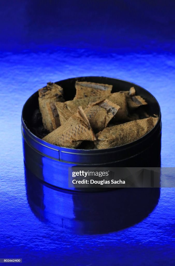 Container of Chewing Tobacco pouches on a blue background