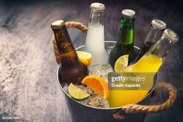 kalte flaschen verschiedener getränke in den eiskübel - softdrinks bottle stock-fotos und bilder