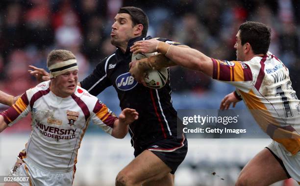 Wigan's Trent Barrett runs between Hudderfields Luke Robinson and Stephen Wild during the Engage Super League match between Huddersfield Giants v...