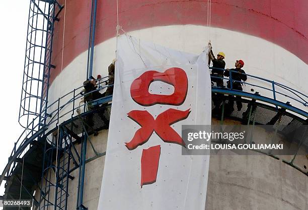 Power line workers hang a protest banner on a 160m high chimney stack at a public electricity plant near Athens on March 16, 2008. Striking workers...