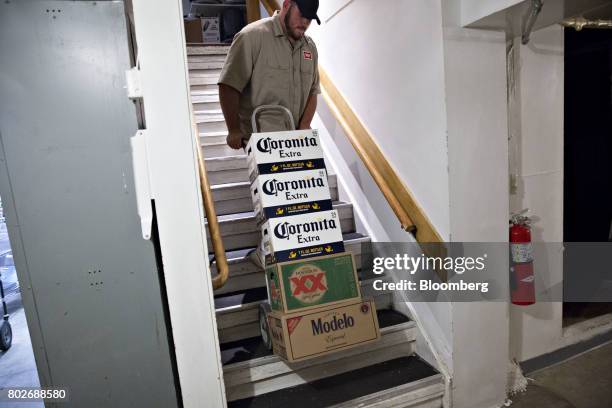 Worker pulls cases of Constellation Brands Inc. Corona and Modelo beer up a staircase during a delivery in Ottawa, Illinois, U.S., on Tuesday, June...