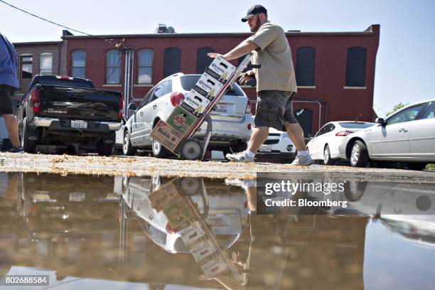 Worker pushes cases of Constellation Brands Inc. Corona and Modelo beer during a delivery in Ottawa, Illinois, U.S., on Tuesday, June 27, 2017....