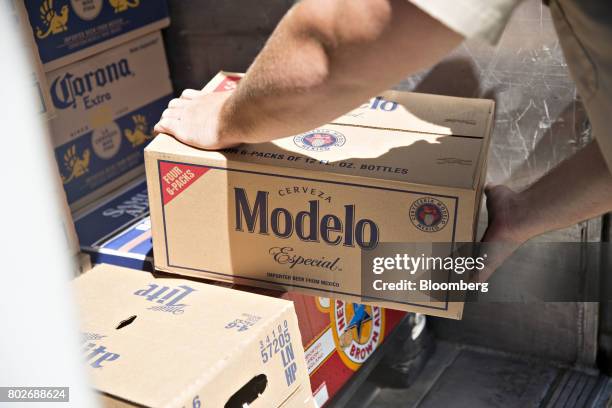 Worker unloads a case of Constellation Brands Inc. Modelo beer from truck during a delivery outside a bar in Ottawa, Illinois, U.S., on Tuesday, June...