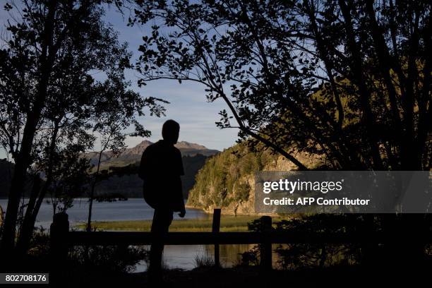 This photo taken on March 19, 2010 shows a man watching the Arrayanes river and Verde lake at Los Alerces national park in the Patagonian province of...