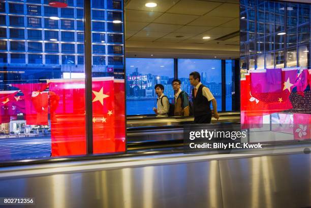 Pedestrians walk on a bridge past a display of National flags of China and Hong Kong ahead of Chinese President Xi Jinping's arrival in Hong Kong on...
