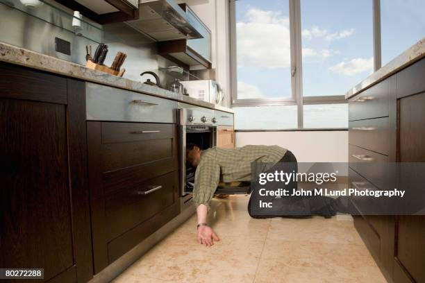 hispanic man laying with head in oven - futility stock pictures, royalty-free photos & images