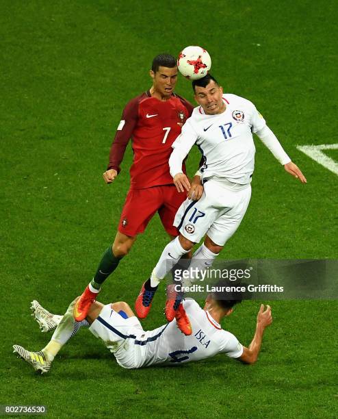 Cristiano Ronaldo of Portugal and Gary Medel of Chile battle to win a header as Mauricio Isla of Chile tackles during the FIFA Confederations Cup...