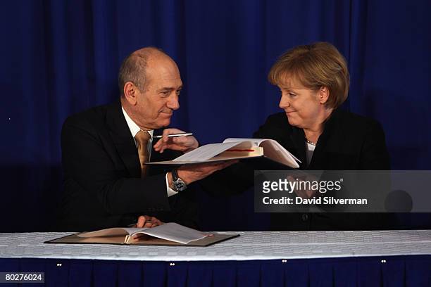 Visiting German Chancellor Angela Merkel and her host Israeli Prime Minister Ehud Olmert sign a bilateral cooperation agreement during their joint...