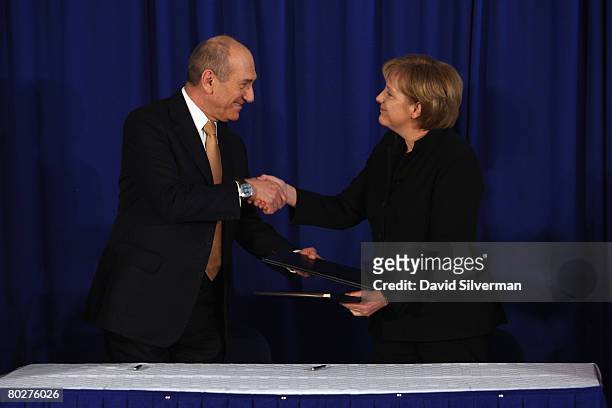 Visiting German Chancellor Angela Merkel and her host Israeli Prime Minister Ehud Olmert shake hands as they conclude signing a bilateral cooperation...