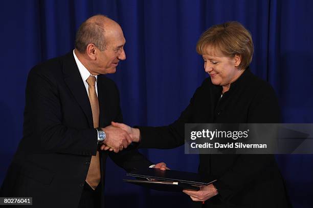 Visiting German Chancellor Angela Merkel and her host Israeli Prime Minister Ehud Olmert shake hands as they conclude signing a bilateral cooperation...