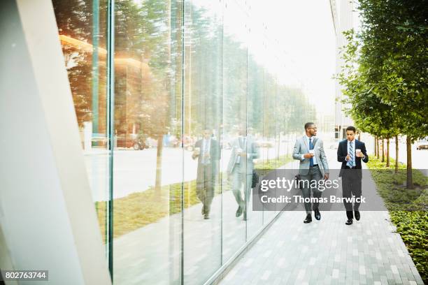 two businessmen in discussion walking on city sidewalk - business people outside stock-fotos und bilder