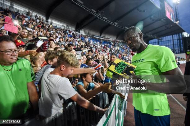 Usain Bolt of Jamaica signs book of his fan after he finished the line at the 100 meters men IAAF World challenge Zlata Tretra in Ostrava, Czech...