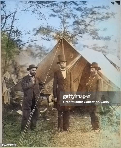 President Abraham Lincoln, flanked by civil war officials, standing outside of a tent, 1863. Image courtesy National Archives. Note: Image has been...