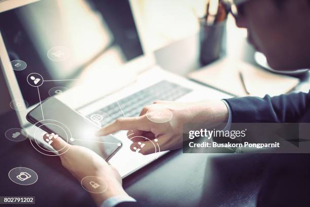 businessman hand working with mobile phone and laptop computer  with technology digital graphic - mobile technology stockfoto's en -beelden