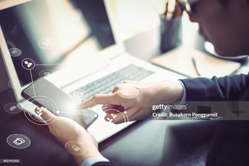 Businessman hand working with mobile phone and laptop computer  with technology digital graphic