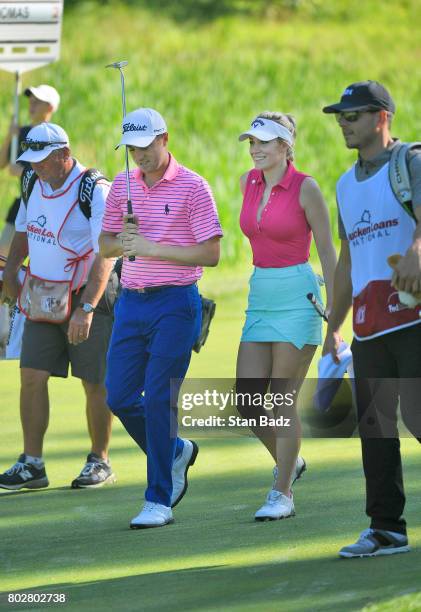 Justin Thomas and Paige Spiranac walk along the seventh hole during the Pro-Am round for the Quicken Loans National at TPC Potomac at Avenel Farm on...