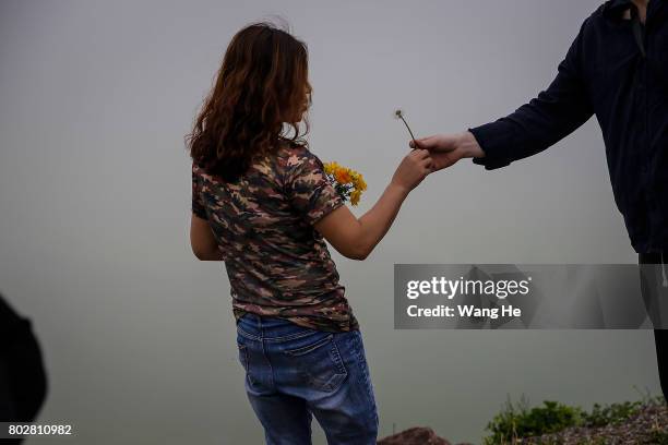 Woman is handed a dandelion while standing roadside to the Duku highway on June 28.017 in Xinjiang Uygur Autonomous Region, China. The Duku highway...