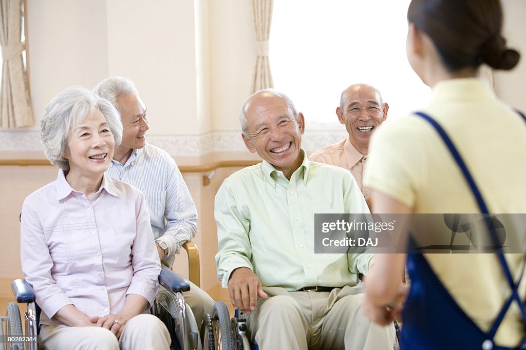 Senior people smiling and listening to female nurse