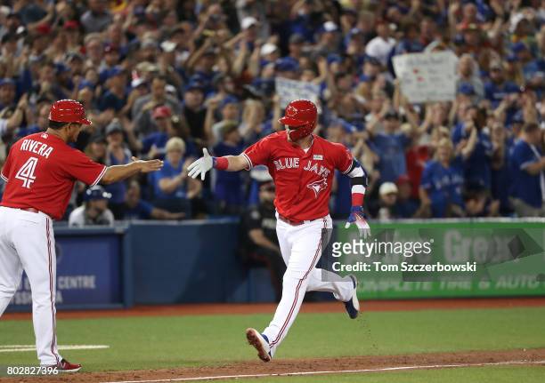 Josh Donaldson of the Toronto Blue Jays is congratulated by third base coach Luis Rivera as he circles the bases after hitting a solo home run in the...