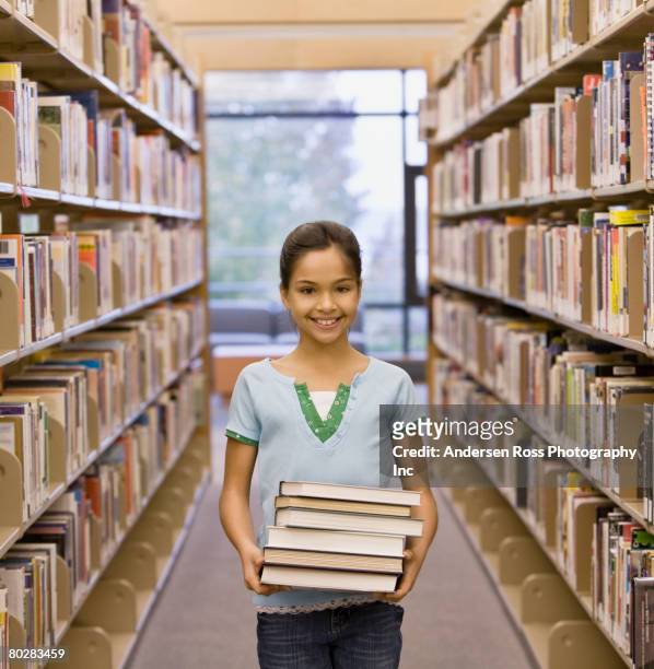 mixed race girl holding stack of library books - ragazza scuola foto e immagini stock
