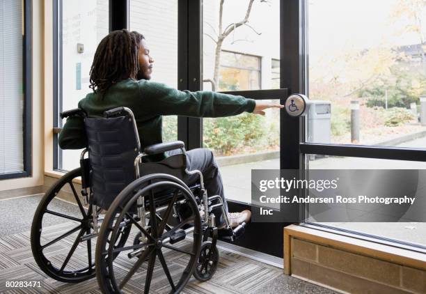 african man in wheelchair using automatic door - barrierefreiheit stock-fotos und bilder