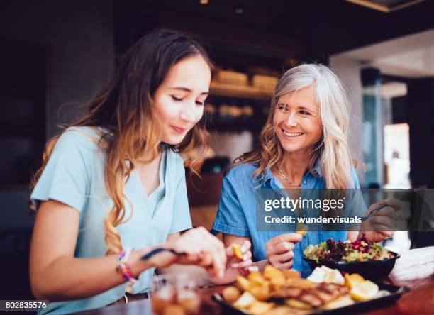 hermosa madre senior e hija comer juntos el almuerzo en el restaurante - día de la madre fotografías e imágenes de stock