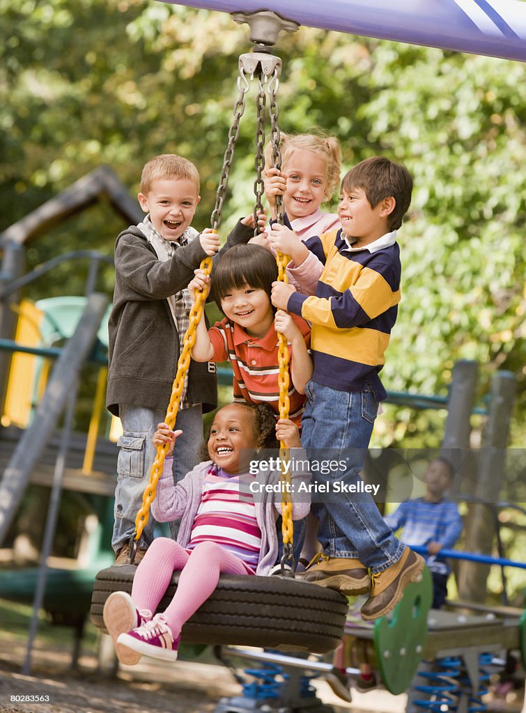 Multi-ethnic children playing on tire swing