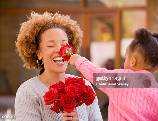 african girl giving flowers to mother - mothers day flowers stock pictures, royalty-free photos & images