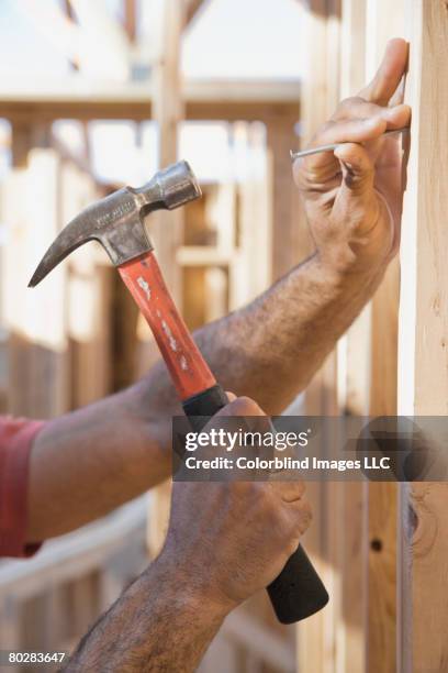 mixed race male construction worker hammering nail - hammer and nail fotografías e imágenes de stock