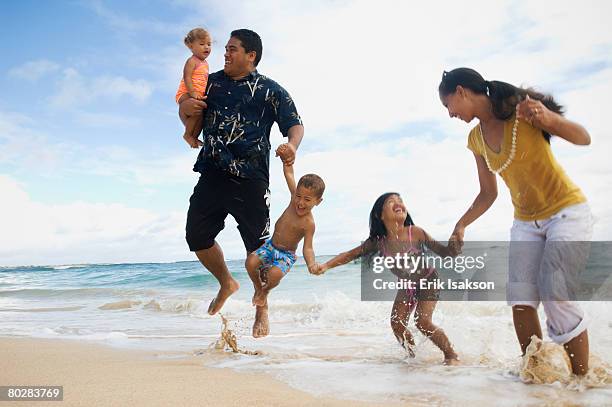 pacific islander family jumping in ocean surf - habitant des îles du pacifique photos et images de collection