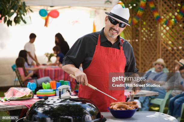 hispanic man barbecuing - bbq father stock-fotos und bilder